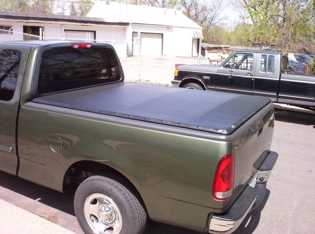 Dark green Ford F-150 pickup rear quarter view with black snap-on tonneau cover over the bed
