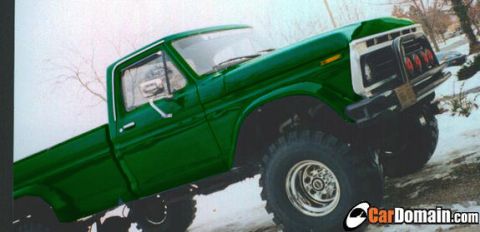 1990 Ford Bronco - This lifted green pickup truck features a distinctive front grille and large off-road tires.