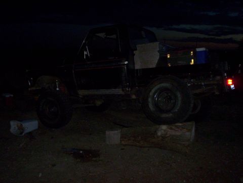1978 Ford Bronco - A black 1978 Ford Bronco is propped up on a log, with a cooler in the bed.