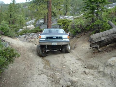 1989 Ford Bronco - Ford F-Series truck navigates a challenging off-road trail with steep inclines and large rocks.