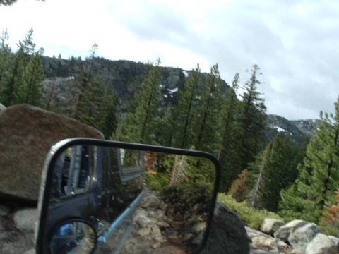 1989 Ford Bronco - A vehicle's side mirror reflects the interior and exterior, showing a mountainous, wooded terrain.