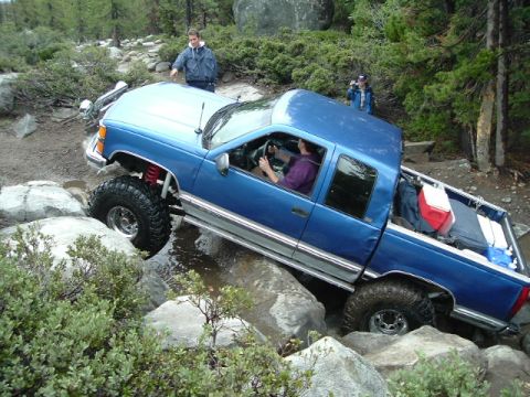 1989 Ford Bronco - A blue pickup truck is shown off-roading on a rocky trail.