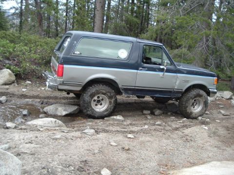 1989 Ford Bronco - This two-tone blue and silver Ford Bronco navigates a challenging rocky path during an off-road excursion.