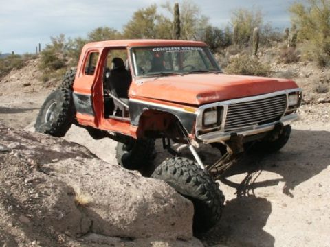 1978 Ford Bronco - Modified 1978 Ford Bronco navigates rocky terrain with one wheel lifted.