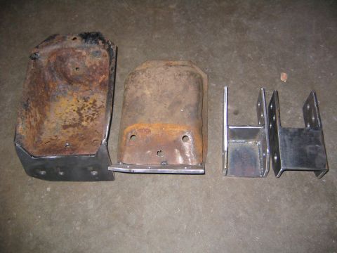 1978 Ford Bronco - Four fabricated steel mounting brackets laid out on a concrete floor: two large multi-hole frame brackets showing heavy surface rust and ol…