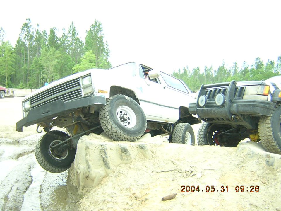 White K5 Blazer and Jeep Cherokee off-roading on a dirt mound
