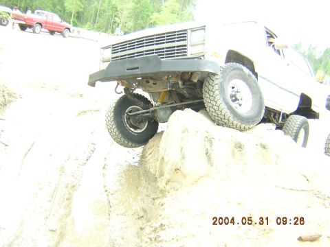 1984 Chevrolet Blazer - A white SUV navigates a challenging off-road course with a red truck visible in the background.