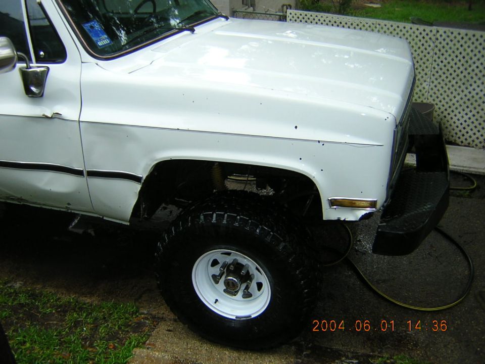 White 1984 Chevrolet K5 Blazer front fender and hood detail, showing off-road tires and aftermarket bumper