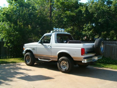 1996 Ford Bronco - This Ford Bronco is parked in a driveway with trees in the background.