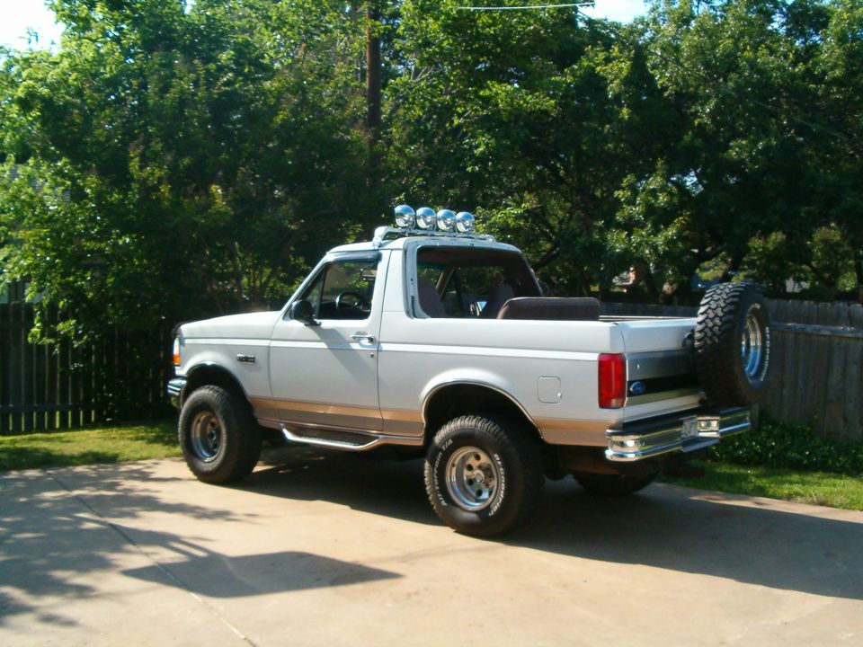 Light blue and tan two-tone Ford Bronco with roof lights and rear-mounted spare, top removed