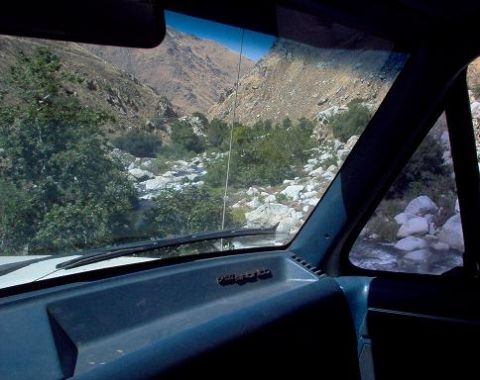 1988 Ford Bronco - The view from inside a vehicle shows a mountain landscape with a river flowing through it.