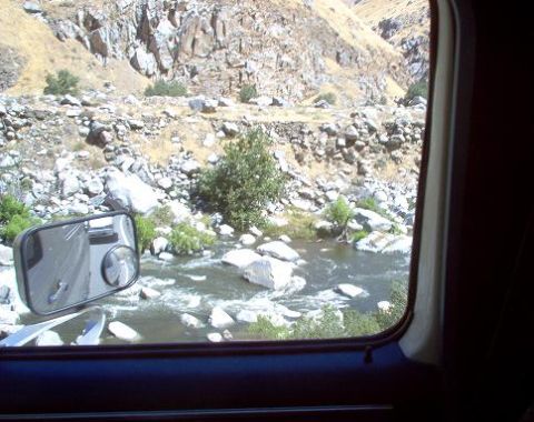 1988 Ford Bronco - View from inside a vehicle shows a side mirror and a scenic landscape with a river and rocky hills.