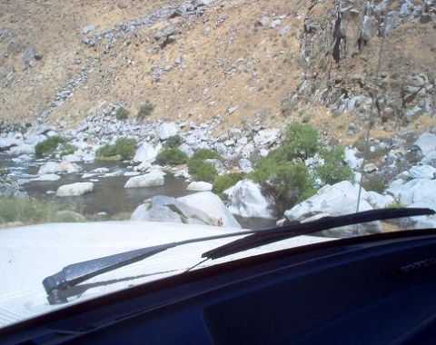 1988 Ford Bronco - View from inside a vehicle as it navigates a rocky terrain alongside a river.