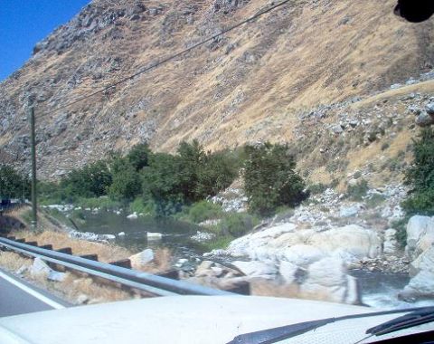1988 Ford Bronco - View from inside a vehicle looking out at a river flowing past a rocky, dry hillside.
