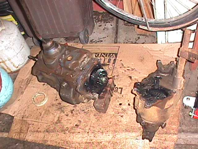 Two disassembled automotive transmission and transfer case components on cardboard