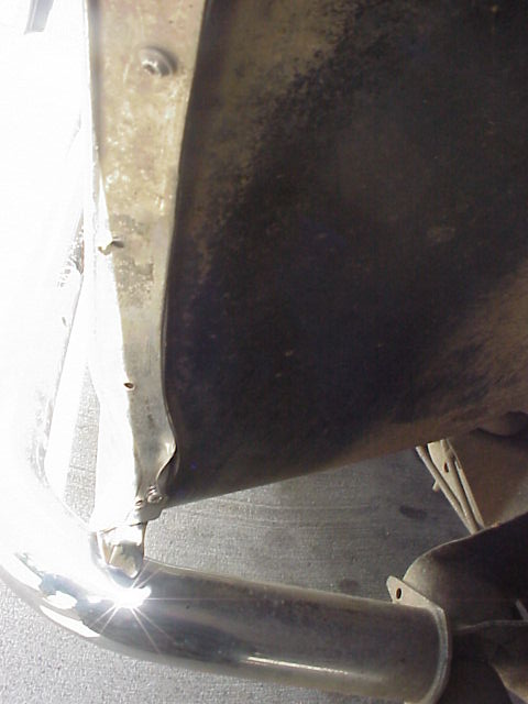 1989 Ford Bronco - Close-up view of the underside of a vehicle's wheel well, revealing a chrome exhaust pipe and the inner fender liner.