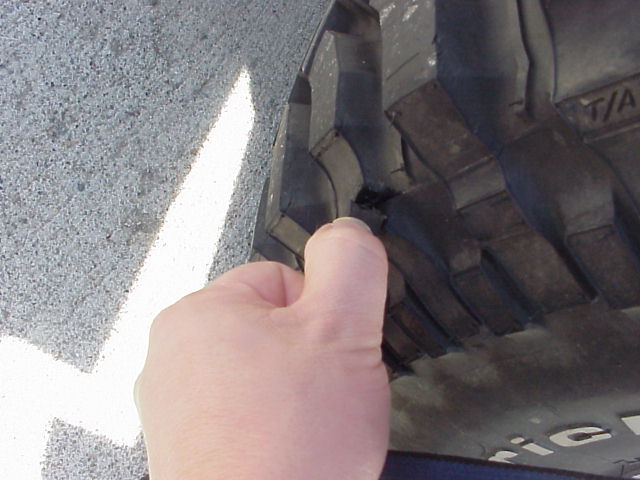 hand touching a tire tread with "T/A" visible on the sidewall