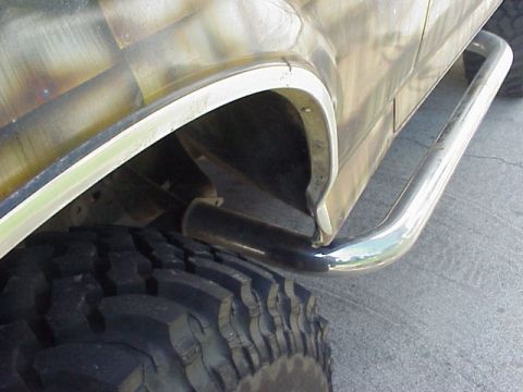 1989 Ford Bronco - Close-up of a vehicle's rear wheel well, large tire, and side step. The registry claims 1989 Ford Bronco, but this is not verifiable from t…