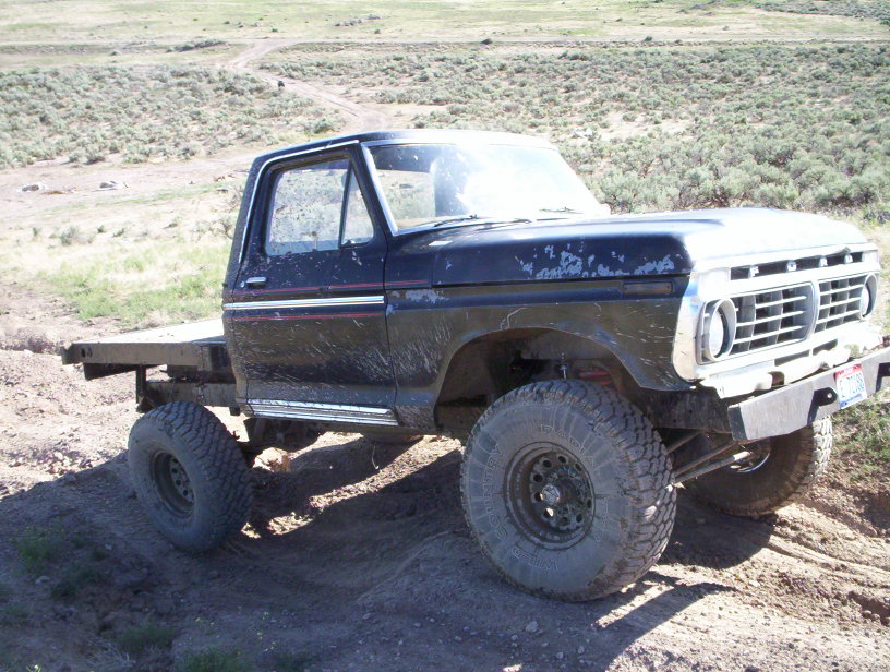 Black flatbed truck with off-road tires and a 1975 grille