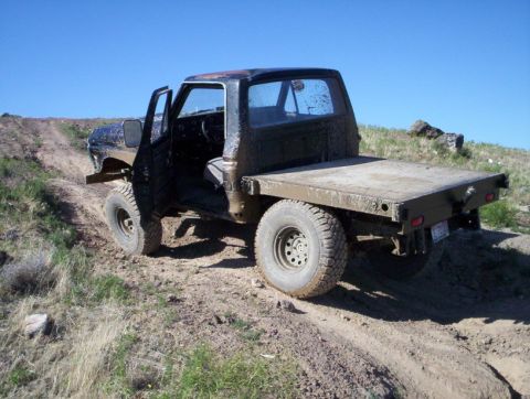 1978 Ford Bronco - Flatbed truck navigating a dirt path under a clear blue sky.