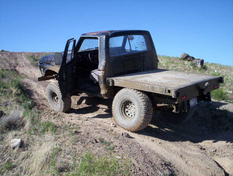 Flatbed truck with doors open driving on a dirt road