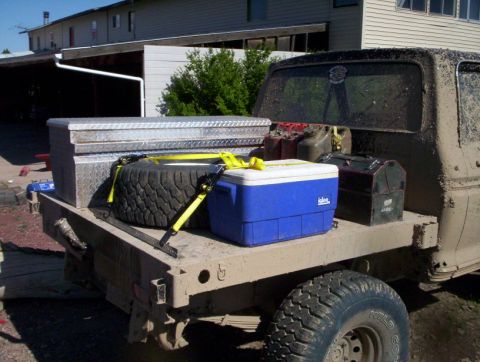 1978 Ford Bronco - Flatbed truck bed loaded with gear, including a toolbox, spare tire, cooler, and gas cans.