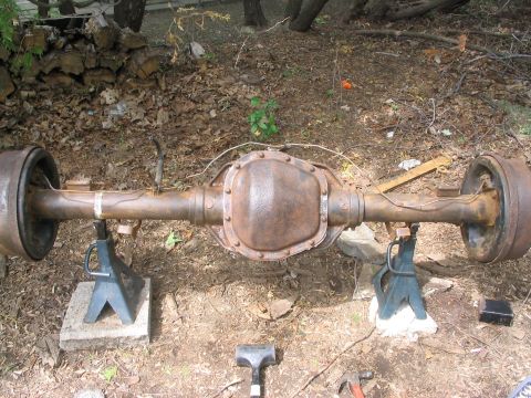 1986 Ford Bronco - This rusty rear axle assembly is supported by jack stands in an outdoor setting.