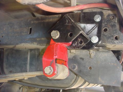1988 Ford Bronco - Close-up view of a red shackle flip kit installed on a vehicle's frame.