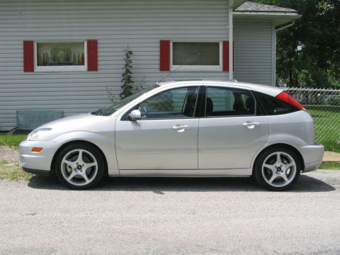 2003 Ford Focus - This silver hatchback is parked on a gravel driveway in front of a light-colored house.