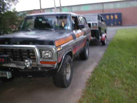 1979 Ford Bronco - This 1979 Ford Bronco is seen from the front 3/4 angle, driving down a road with another vehicle following.