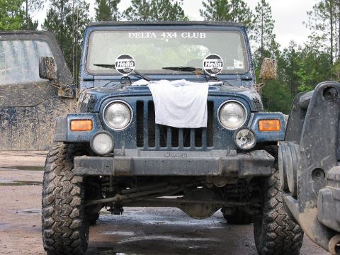 2002 Jeep Wrangler - A muddy blue 2002 Jeep Wrangler is parked next to another off-road vehicle, with "DELTA 4X4 CLUB" visible on the windshield.