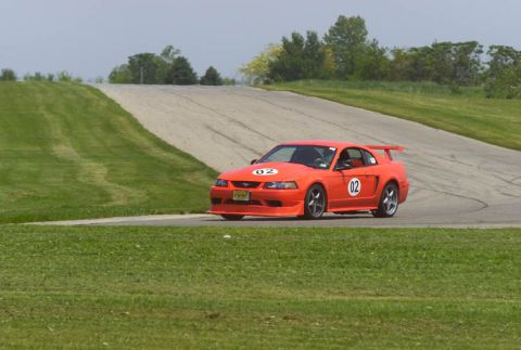 2000 Ford Mustang - A bright orange 2000 Ford Mustang races on a track, displaying the number 02.