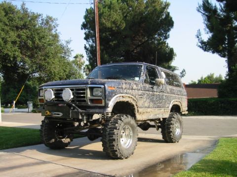 1985 Ford Bronco - This heavily modified Ford Bronco shows off its lifted suspension and off-road tires, covered in mud from recent adventures.