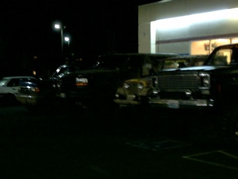1995 Ford Bronco - Several vehicles are parked in a lot at night, with a Jeep CJ-7 prominently in the foreground.