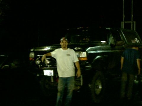 1995 Ford Bronco - A man poses with a black 1995 Ford Bronco, captured at night.