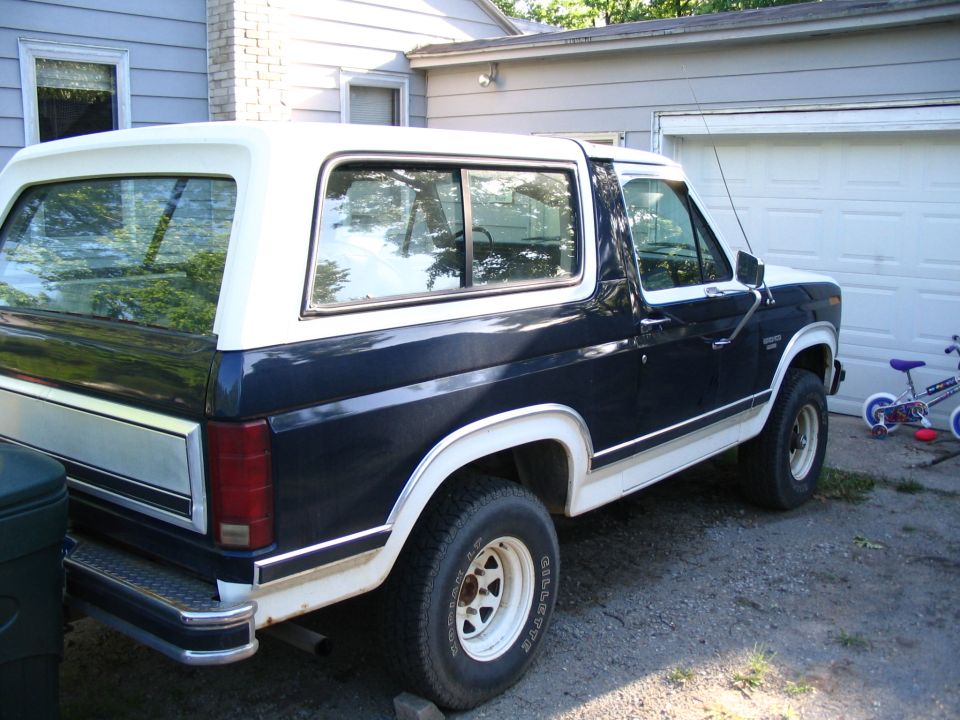 Dark blue and white Ford Bronco parked in driveway, rear quarter view