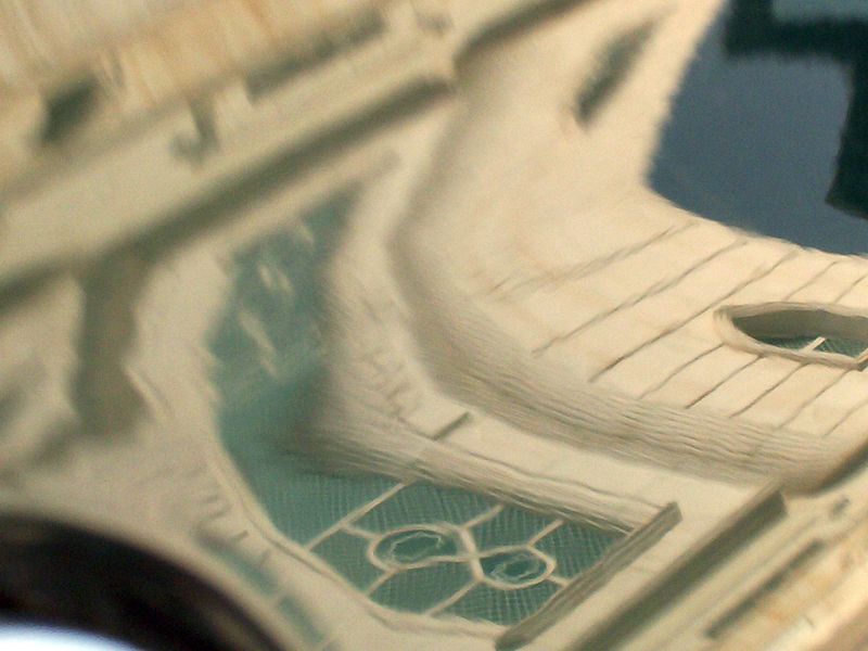 Macro of a cream sculpted roof and arched window relief over a teal background