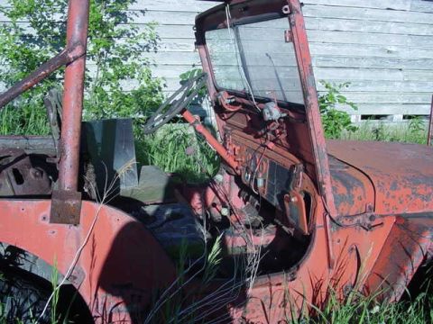 1992 Ford Bronco - An old, weathered jeep sits abandoned, partially obscured by tall grass and weeds.