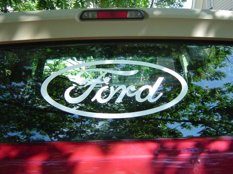 1995 Ford Bronco - A white Ford oval logo is affixed to the rear window of a red vehicle.