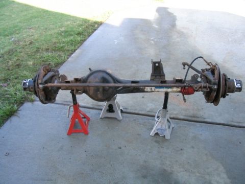 1986 Ford F-150 - A disassembled rear axle assembly is supported by jack stands on a concrete surface.