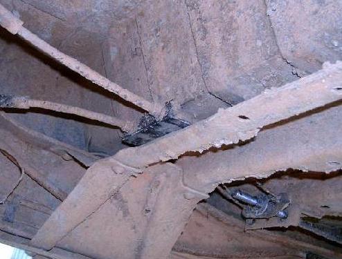 Mud-caked truck undercarriage showing frame rail, crossmember and body mount