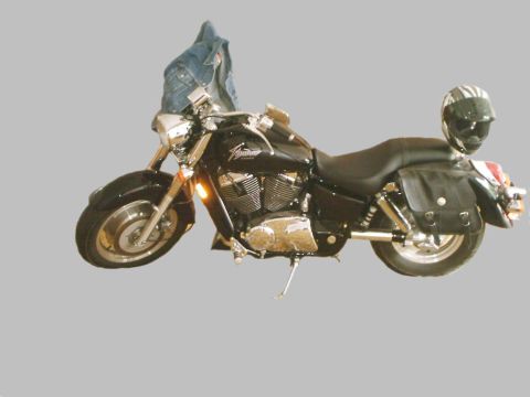 1989 Ford Bronco - A black motorcycle is shown from the side, equipped with saddlebags and a helmet resting on the seat.