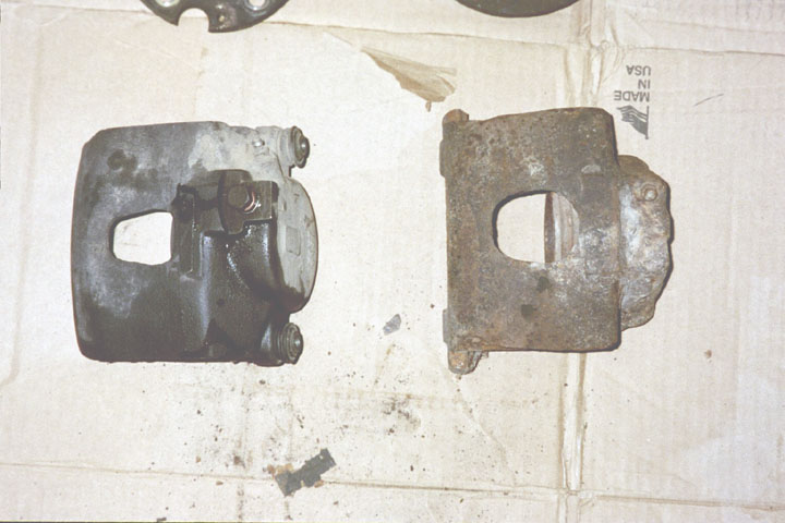 Two brake calipers, one looks used and dirty, the other is heavily rusted