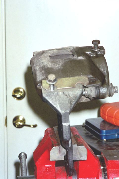 1994 Ford Bronco - A brake caliper is secured in a vise, ready for maintenance or repair.