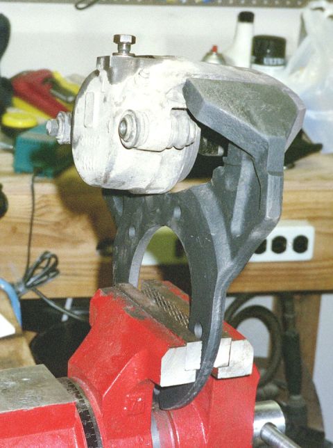 1994 Ford Bronco - A brake caliper is secured in a red vise, likely for repair or maintenance.