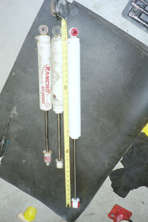1994 Ford Bronco - A measuring tape is used to show the lengths of three shock absorbers, two of which are branded Rancho RS5000.