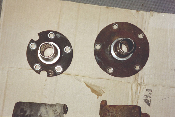 Two rusty wheel hubs with bolt holes on a cardboard surface