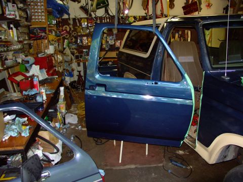 1986 Ford Bronco - Newly painted new door shell hanging by bungees, ready to be bolted onto newly bushed and pinned hinges (see elsewhere). I had to add two w…