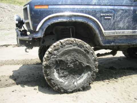 1985 Ford Bronco - Mud-caked tire on a 1985 Ford Bronco, showing off-road use.