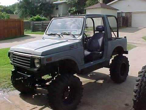 1978 Ford Bronco - Modified Suzuki Samurai parked on a driveway with a suburban house in the background.